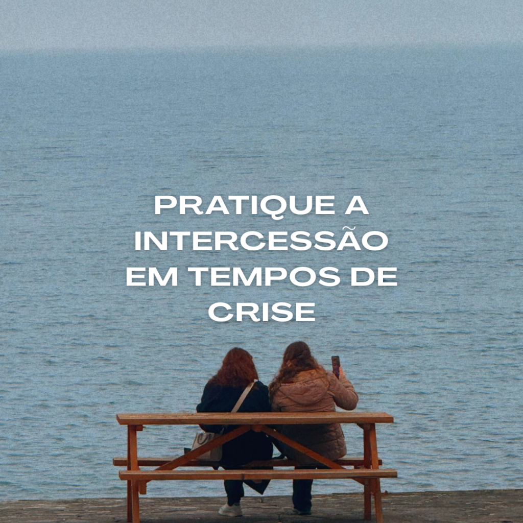 Duas mulheres sentadas em um banco de madeira de frente para o mar, observando o horizonte, com o texto “Pratique a intercessão em tempos de crise” sobreposto à imagem, transmitindo uma mensagem de oração, esperança e confiança em Deus.